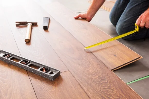 Person misst Laminat mit Maßband aus